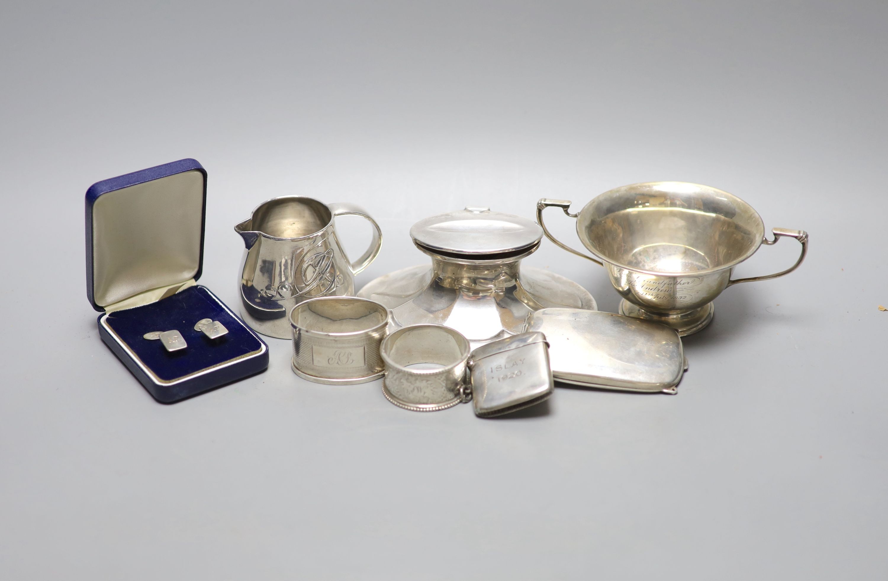 A Scottish silver mounted oval inkwell, 13.2cm, a small silver bowl, silver vesta case, silver cigarette case, two silver napkin rings and two other items.